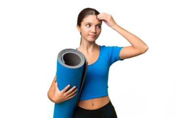 Teenager caucasian girl going to yoga classes while holding a mat over isolated background having doubts and with confuse face expression