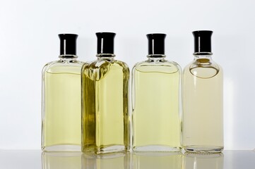 Transparent, glass jars with perfume liquid stand on a white surface