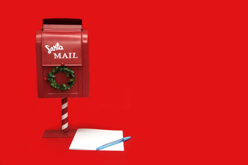 Santa's mailbox with blank paper and pen on red background with copy space