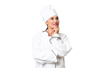 Middle-aged chef woman over isolated background thinking an idea while looking up