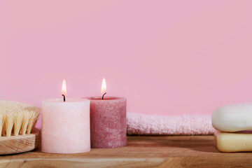 Fototapeta na wymiar Pink spa still life with candles, towel, body brush, soap and rose on wooden desk - ready for aromatherapy and bath