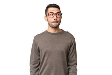 Young handsome caucasian man over isolated background having doubts while looking up