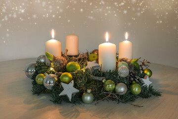 Third Advent, wreath with three burning white candles and green Christmas decoration on a table, home decor for the third Sunday, copy space, selected focus