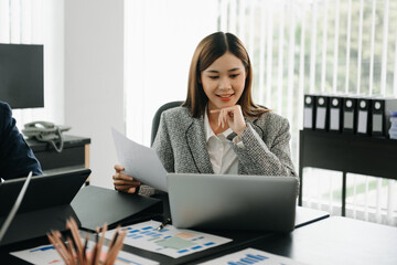 Confident Asian woman with a smile standing holding notepad and tablet at th office..