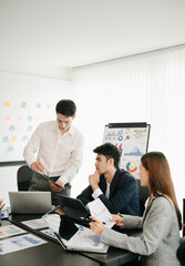 Office colleagues have a casual discussion. During a meeting in a conference room, a group of business teem sit in the conference room