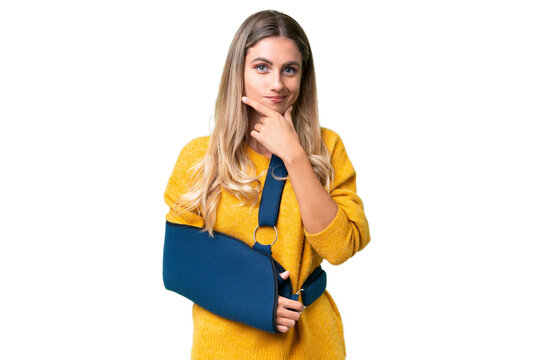 Young Uruguayan woman with broken arm and wearing a sling over isolated background thinking
