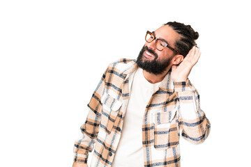 Young man with beard over isolated chroma key background listening to something by putting hand on...