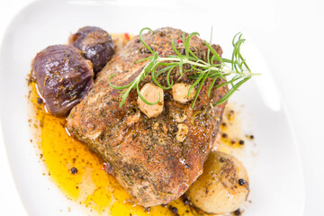 Roast pork loin with onions and garlic, decorated with rosemary and some colorful peppercorns