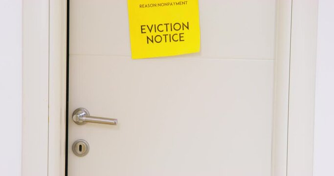 Yellow sheet eviction notice hangs white door moving camera up down close-up. Door ajar court notice rent debts financial problems. Financial planning investment secured old age. Mortgage loan default