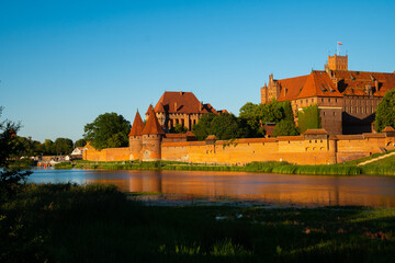 Naklejka na ściany i meble Marienburg Castle the largest medieval brick castle in the world in the city of Malbork at sunset
