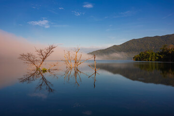 The water reflection of the sunrise breathtaking beauty nature scenery landscape with mountain mist in Khuean Phluang Reservoir nearby Khao Khitchakut National Park, Chanthaburi, Thailand
