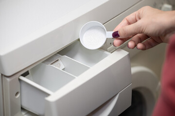 man pouring washing powder into the washing machine.