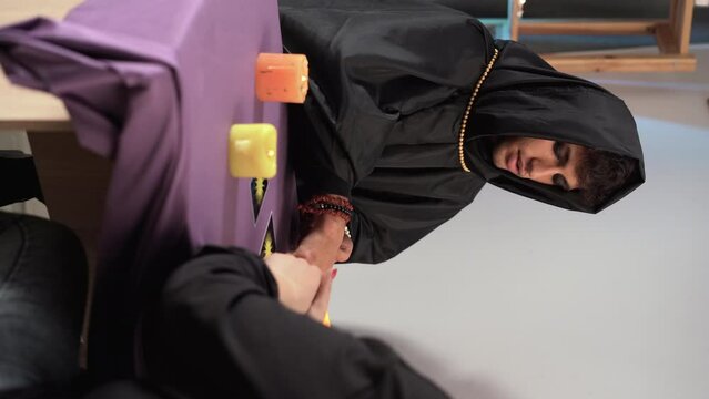 Tarot reading or fortune teller reading tarot cards for his client hands with burning candles and tarot cards on a wooden table.Divination or forecasting concept.