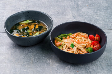 Asian lunch udon noodles with fish salmon and miso soup with tofu, seaweed, onions and shiitake...