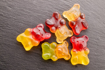 Several gummy bears on slate stone, macro, top view.
