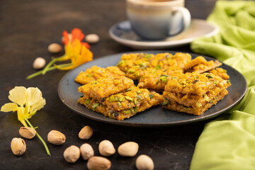 Traditional iranian dessert sohan with cup of green tea on a black concrete background. side view, close up.