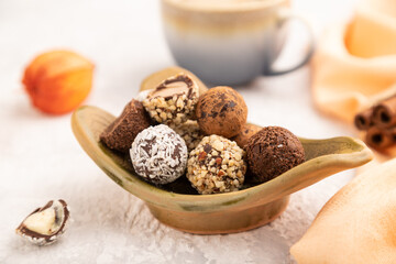 Chocolate truffle candies with cup of coffee on a gray concrete background. side view, close up, selective focus.