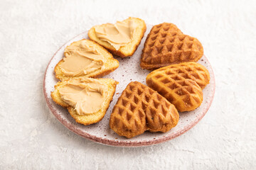 Homemade waffle with peanut butter on a gray concrete. side view, close up.