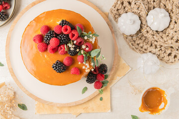 Delicious chocolate cake topped with mascarpone cream and salted caramel. Decorated with red fruits. Light background
