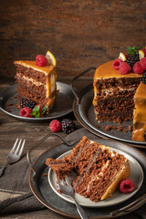 Delicious semi-naked chocolate cake with caramel topping and decorated with blackberries and raspberries. Dark background