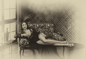 1920s style Happy sexy flapper woman sitting on sofa, short black dress ostrich feather. girl...