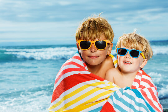 Close portrait of two little boys covered in towel over sea