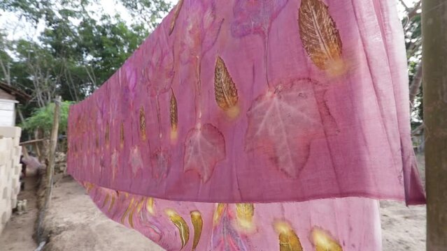 Ecoprint batik fabric with a pink leaf pattern, swaying in the wind when it is dried in the sun.