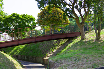 Fototapeta na wymiar 青空のゴルフ場・丘に挟まれ囲まれた川のようなカート道とその上を通る錆びて古い橋（千葉県木更津市）