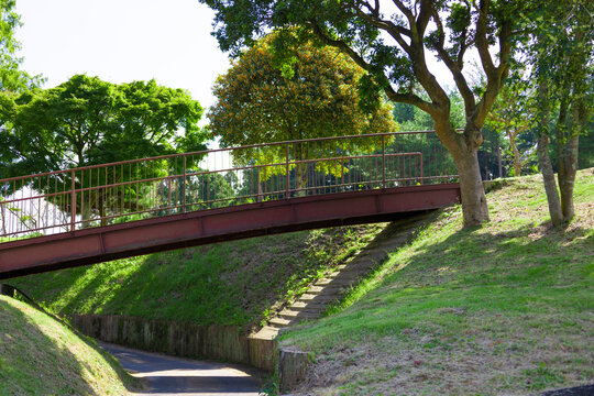 青空のゴルフ場・丘に挟まれ囲まれた川のようなカート道とその上を通る錆びて古い橋（千葉県木更津市）