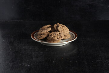 Chocolate chip cookies on plate on black background