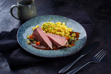 Tafelspitz Braten vom Kalb mit schwäbischen Spätzle and Gemüse serviert mit Dunkelbier Sauce als close-up auf einem Nordic Design Teller 