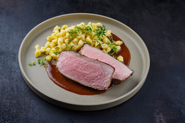 Tafelspitz Braten Scheiben vom Kalb mit schwäbische Spärtle serviert mit Dunkelbier Sauce als close-up auf einem Design Teller 