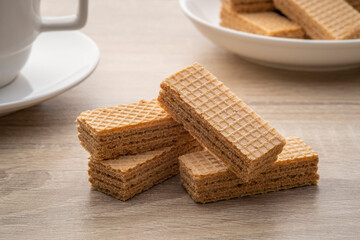Heap of Wafer with coffee flavored cream on wooden plate with cup and coffee bean background