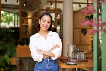 Portrait of smiling asian girl in white collar shirt, working in cafe, managing restaurant, looking...