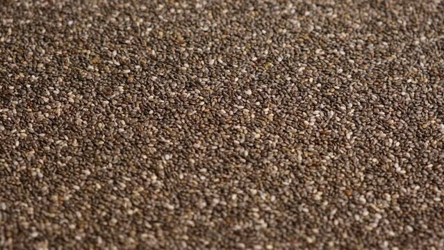 Chia Seeds Wallpaper. Raw Chia Seeds Rotating on Turntable. Close Up, Top View, Macro. Superfood. Spinning. Full Frame. Food Background. Shiny textured White, Gray and Brown Chia. Paleo Diet Concept.