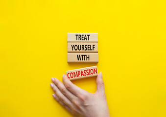 Treat yourself with compassion symbol. Concept words Treat yourself with compassion on wooden blocks. Beautiful yellow background. Doctor hand. Medicine concept. Copy space.