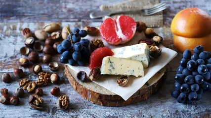 Cheeseboard. Cheese with nuts, grapefruit and grapes on a wooden board. Healthy snacks.
