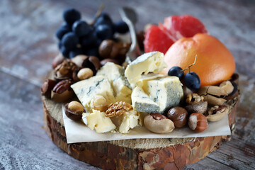 Cheeseboard. Cheese with nuts, grapefruit and grapes on a wooden board. Healthy snacks.