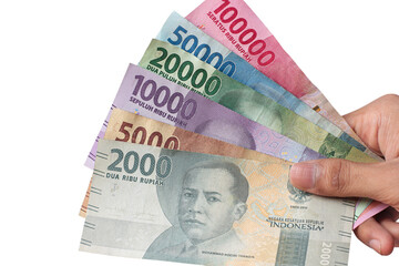 man's hand holding Indonesian rupiah banknotes