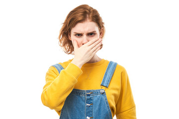 Redhead young woman holding nose to avoid disgusted smell, pinches nose and mouth with fingers and...