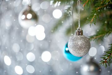 Small Christmas balls on a Christmas tree on a silver bokeh background with snowflakes