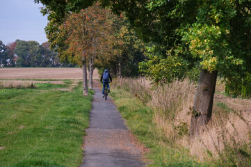 Mittelentfernter Blick auf einen Fahrradfahrer mit Rucksack und Helm auf einem asphaltierten...