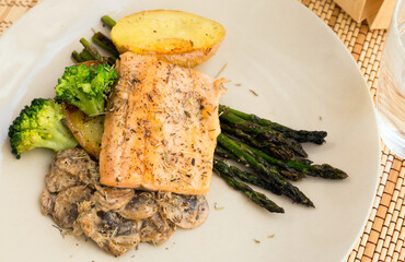 dish of fried river trout fillet with garnish of broccoli, asparagus sprouts and mushroom sauce