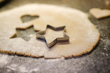 Cutting out star-shaped christmas cookies of a gingerbread dough. 