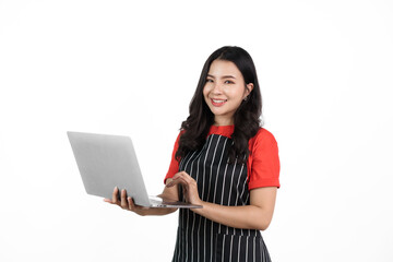 Using laptop, Food shop owner concept, Smiling young confident asian woman in black apron and red t-shirt isolated on white background.