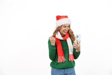 Attractive excited asian female in green sweater with santa hat on christmas isolated on white background. holding mobile smartphone