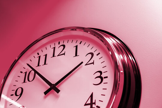part of wall clock face on pink background. time management or opening hours. Summer or winter daylight saving time change.Viva Magenta color of the year 2023