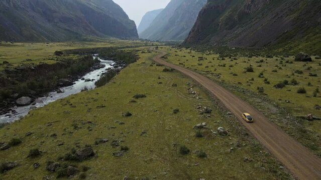 Aerial view of the picturesque valley. Car rides along the river on the road