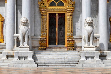 Pair of marble lions in front of the door of Wat Benchamabophit Dusit Wanaram (This temple is known as the Marble Temple) in Bangkok, blue sky and clouds. One of the most beautiful Thailand temples