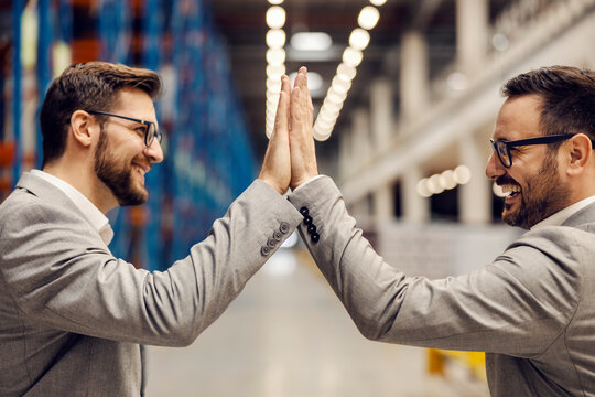 Successful business and collaboration. Businessmen giving high five to each other in warehouse.